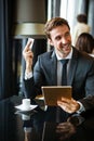 Successful handsome business man holding credit card, using digital tablet. Online shopping concept Royalty Free Stock Photo