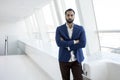 Successful handsome businessman in a blue suit stands against the background of a white office and looks out the window, portrait Royalty Free Stock Photo