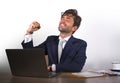 Successful handsome businessman in suit working at office computer desk celebrating financial success winning money smiling cheerf Royalty Free Stock Photo