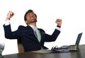 Successful handsome businessman in suit working at office computer desk celebrating financial success winning money smiling cheerf Royalty Free Stock Photo