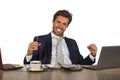 Successful handsome businessman in suit working at office computer desk celebrating financial success winning money smiling cheerf Royalty Free Stock Photo