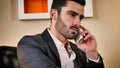 Smiling handsome young businessman at desk on phone Royalty Free Stock Photo