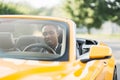 Shot of a mature African American man smiling and looking away while sitting in his yellow car Royalty Free Stock Photo