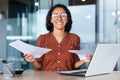 Successful and happy businesswoman satisfied with achievement results, smiling and looking at camera holding documents Royalty Free Stock Photo