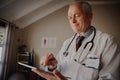 Successful and happy mature doctor wearing labcoat and stethoscope using digital tablet Royalty Free Stock Photo