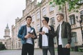 Successful happy students standing near campus or university outside