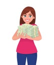 Successful happy young business woman holding cash / money / currency / banknote bundle in hands. Business and finance concept.