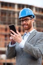 Successful young architect or businessman standing at the construction site, browsing internet Royalty Free Stock Photo