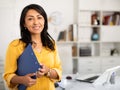 Successful Hispanic business woman with folder of documents in office