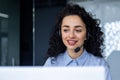 Successful hispanic woman with headset phone for video call working with laptop while sitting at workplace, online Royalty Free Stock Photo