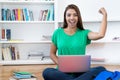 Successful hispanic young adult female student learning online at computer