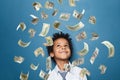 Successful little black kid boy standing under us dollar money rain on blue background Royalty Free Stock Photo