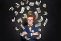 Successful little kid boy standing with crossed hands under us dollar money rain on black background Royalty Free Stock Photo