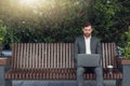 Successful male businessman working on laptop at lunchtime sitting on bench near office Royalty Free Stock Photo