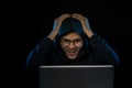 Successful male hacker poses in front of laptop computer, clenches fists, dressed in black clothes, rejoices finishing bad data Royalty Free Stock Photo