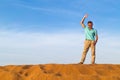 The successful man waves a hand from dune top in the desert Royalty Free Stock Photo