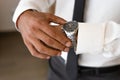 Successful man with white shirt and necktie looks on watch