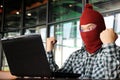 Successful masked hacker wearing a balaclava raising hands after stealing important information data with laptop. Network security Royalty Free Stock Photo