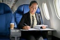 A successful mature Asian businesswoman focuses on reviewing business reports during the flight Royalty Free Stock Photo