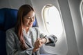 Successful millennial Asian businesswoman on the plane, checking a landing time on wristwatch Royalty Free Stock Photo