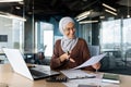 Successful muslim woman in hijab working inside office with documents, joyful financial accountant happy with reports Royalty Free Stock Photo