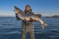 Successful pike fishing. Happy fisherman hold huge muskie fish