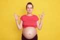 Successful pregnancy. Positive Caucasian girl showing ok sign with both hands, lady with hair bun wearing casual t shirt, shows