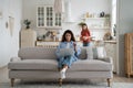 Professional woman freelancer works with laptop sits on couch and daughter with gift box in hands Royalty Free Stock Photo