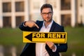 Successful real estate agent in a suit holding for rent sign near new apartment. Real estate agent with home loan Royalty Free Stock Photo