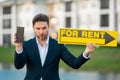 Successful real estate agent in a suit holding for rent sign near new apartment. Realtor or real estate agent shows Royalty Free Stock Photo