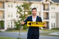 Successful real estate agent in a suit holding for rent sign near new apartment. Realtor or real estate agent shows Royalty Free Stock Photo