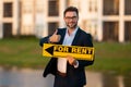 Successful real estate agent in a suit holding for rent sign near new apartment. Realtor or real estate agent shows Royalty Free Stock Photo