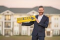 Successful real estate agent in a suit holding for rent sign near new apartment. Real estate agent with rental contract Royalty Free Stock Photo