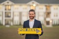Successful real estate agent in a suit holding for rent sign near new apartment. Real estate agent with rental contract Royalty Free Stock Photo
