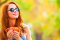 Successful redhead girl winh cup in the autumn park. Royalty Free Stock Photo