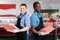 Successful sellers of butcher store offering fresh raw meat steak cutlets Royalty Free Stock Photo