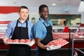 Successful sellers of butcher store offering fresh raw meat steak cutlets Royalty Free Stock Photo