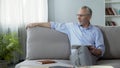 Successful senior man sitting on couch with tablet, using modern gadget for work Royalty Free Stock Photo