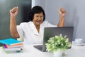Successful senior woman working on laptop with arms raised Royalty Free Stock Photo