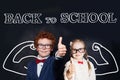 Successful smart kids in school uniform having fun on blackboard background, back to school and brain power concept