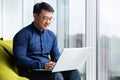 Successful and smiling asian man working with laptop inside office with notebook, senior businessman in glasses and Royalty Free Stock Photo