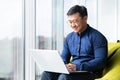 Successful and smiling asian man working with laptop inside office with notebook, senior businessman in glasses and Royalty Free Stock Photo