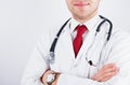 Successful smiling male doctor in medical coat with red tie and phonendoscope crossed his arms over chest Royalty Free Stock Photo