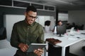 Cheerful young businessman using digital tablet smiling while his colleagues working at the background Royalty Free Stock Photo