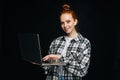 Successful smiling young woman holding laptop computer and looking at camera on black background. Royalty Free Stock Photo