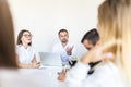 Successful team leader and business owner leading informal in-house business meeting. Businessman working on laptop in foreground Royalty Free Stock Photo