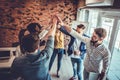 Successful team of young professionals celebrating achievement in work project giving high-five to each other in office Royalty Free Stock Photo