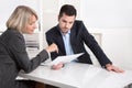 Successful teamwork: businessman and woman sitting at desk talking about reports and finance.