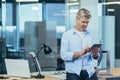 Successful and thoughtful business owner uses a tablet computer, businessman works in a modern office