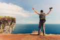 Successful traveler man photographer standing with raised hands on the top mountain cliff on background nature landscape Royalty Free Stock Photo